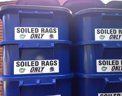 Industrial signage placed on bins to indicate that only soiled rags belong in the bin.